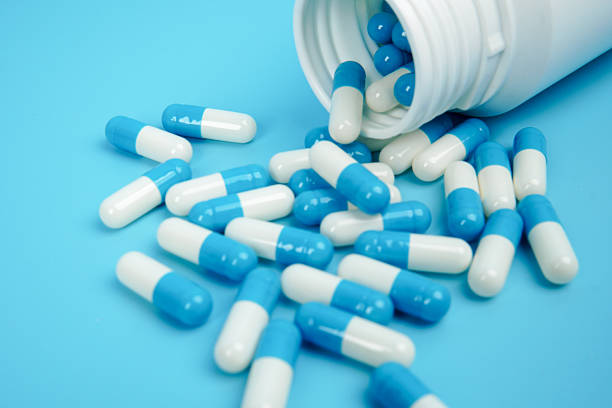 istock Blue and white medicine capsules spilled from bottle representing pharmaceutical supply, healthcare treatment, medication management, and medical industry concept with clean copy space. 2251906633