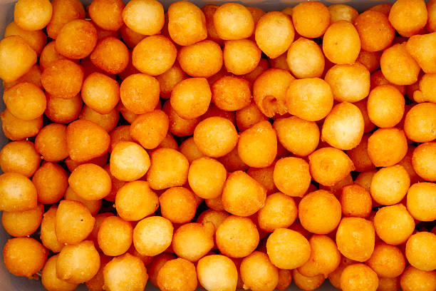 Many small orange cheese balls filling the frame creating a crunchy texture