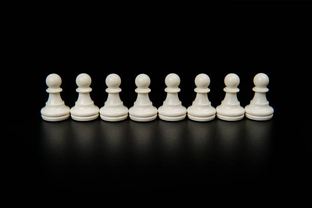 istock Identical white chess pawns aligned in a row on dark background representing equality, standardization, unity, consistency, and balanced teamwork within organizational or business structure. 2251907383