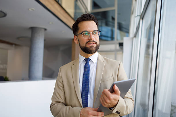istock Confident businessman holding digital tablet, looking away in a modern office building, thinking about future strategies 2251911007