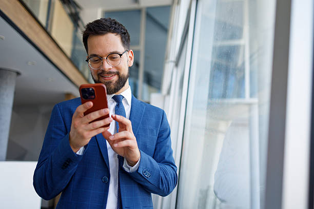 istock Businessman smiling, texting on mobile phone in modern office, staying connected and productive 2251911794