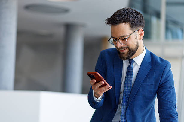 istock Professional businessman using mobile phone checking emails or social media smiling in modern office environment 2251912227