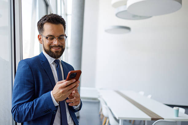 istock Professional businessman checking phone in modern office smiling, working remotely, or taking a break 2251912589