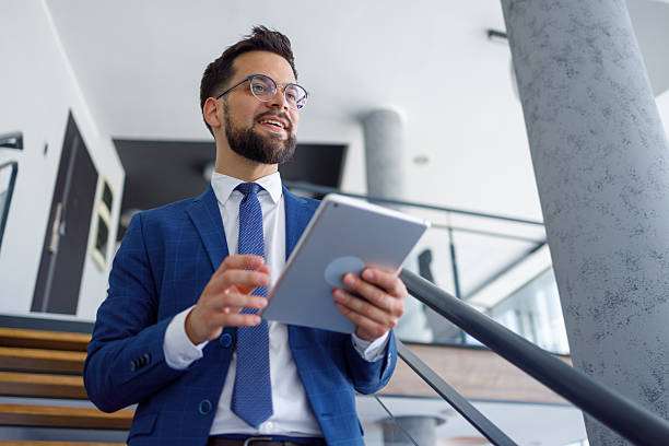 istock Businessman using tablet in a modern office, looking away and thinking about business future 2251913568