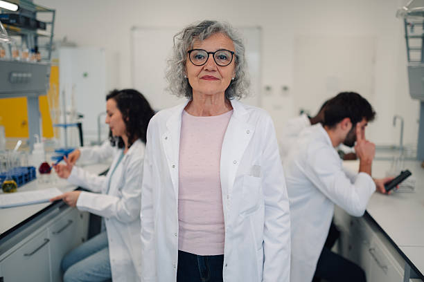 istock Mature female scientist smiling in laboratory with team 2251917755