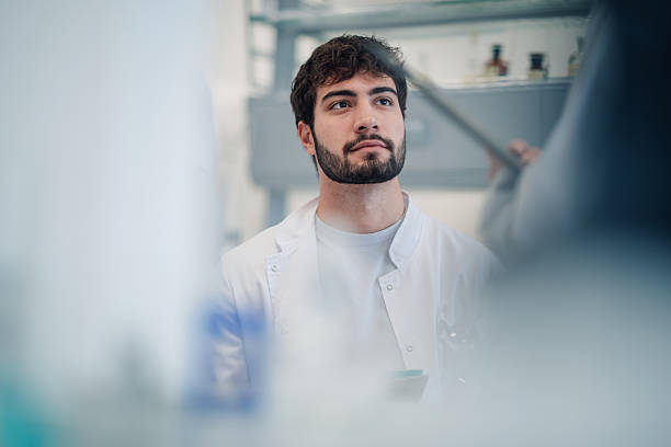 istock Young male scientist in lab coat looking up thoughtfully 2251917784