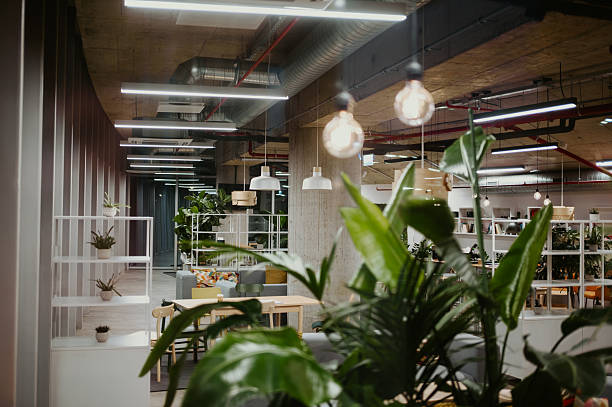 Contemporary open-plan office interior combining industrial elements with lush green plants, creating a refreshing work environment