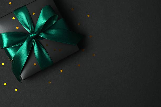 istock Beautiful black gift box tied with green bow on black background 2251920236