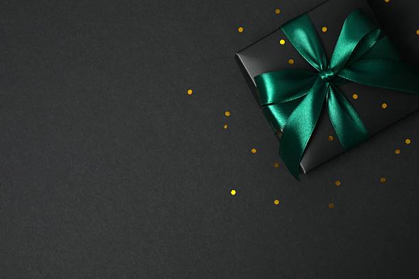 istock Beautiful black gift box tied with green bow on black background 2251920242