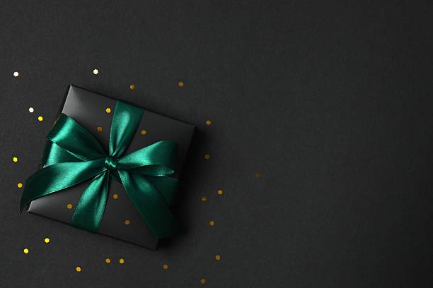 istock Beautiful black gift box tied with green bow on black background 2251920243
