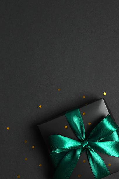 istock Beautiful black gift box tied with green bow on black background 2251920244