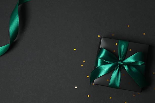 istock Beautiful black gift box tied with green bow on black background 2251920245