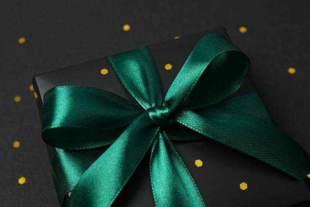 istock Beautiful black gift box tied with green bow on black background 2251920246