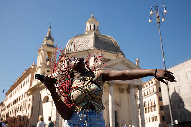 Young woman dancing joyfully while listening to music on her phone at Piazza del Popolo in Rome.