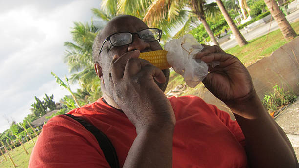 istock A man in glasses and a red shirt eats corn on the cob 2251921760