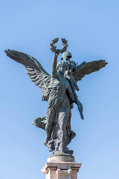 Bronze Winged Victory sculpture on Ponte Vittorio Emanuele II over the Tiber River in Rome, Italy. The monumental allegorical figure, holding a laurel wreath and symbolizing victory, peace, and national unity, was created by Italian sculptors including Elmo Palazzi, Luigi Casadio, Amleto Cataldi, and Francesco Pifferetti and inaugurated in 1911 as part of the bridge honoring King Victor Emmanuel II. Set against a clear blue sky, the statue reflects neoclassical style and Italy’s Risorgimento heritage.