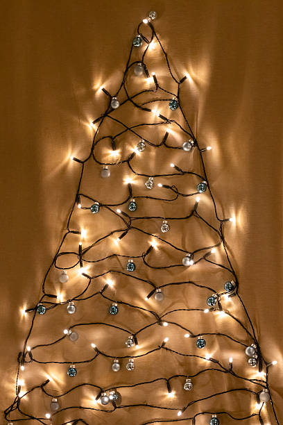 istock Christmas tree shape made from string lights and decorative ornaments on fabric background 2251924560