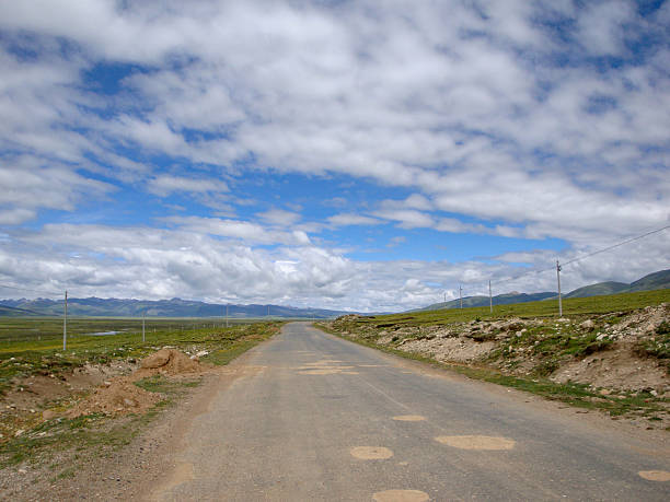 istock Scenic Open Road in Grassland Under Cloudy Sky 2251925518