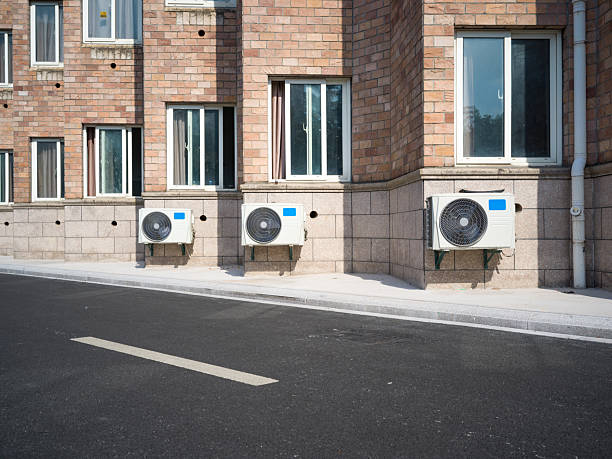 AC unit attached to brick building with white-framed windows