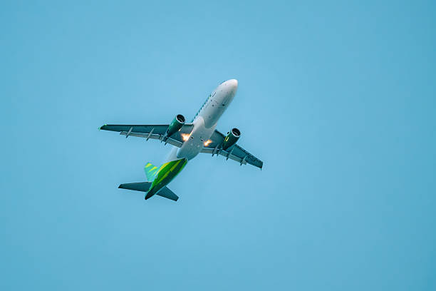 Balikpapan, Indonesia - November 10, 2025. A Citilink Airbus A320 jet viewed from below, showing the bright green tail and fuselage against a clear blue sky as it climbs.