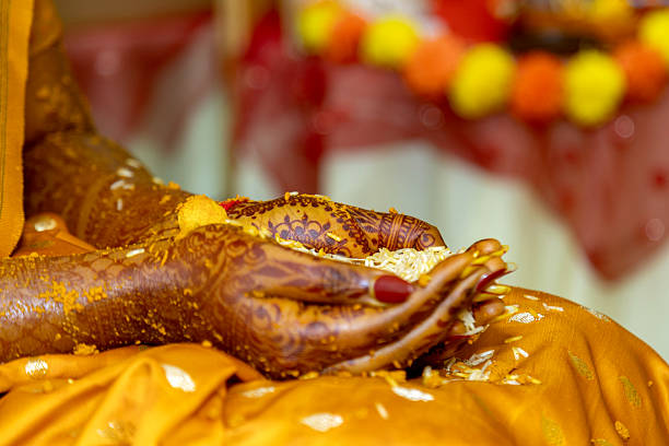 This image captures a close-up of a bride's hands during a traditional Indian wedding ritual, showcasing intricate henna designs