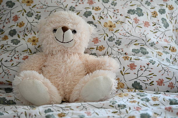 istock White, soft teddy bear in a child's bed with floral pattern bedsheets 2251937137