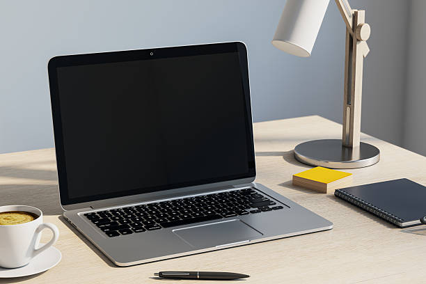 istock Modern workspace with laptop, coffee cup, lamp, and notebook on light wooden desk in natural lighting environment. 3D Rendering 2251941468