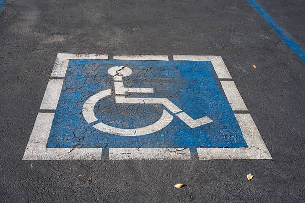 istock Cracked blue and white handicap parking symbol painted on asphalt pavement 2251949594