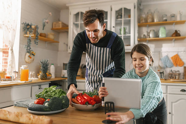 istock Father and daughter using a tablet to follow online recipes while cooking together 2251952258