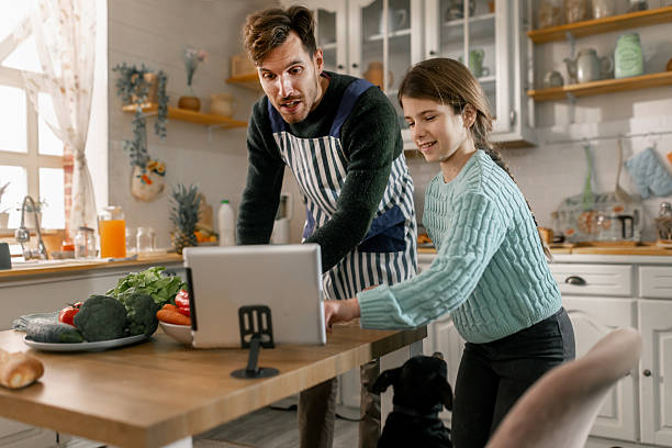 istock Father and daughter using a tablet to follow online recipes while cooking together 2251952259