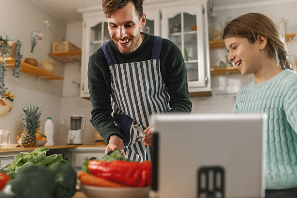 istock Father and daughter using a tablet to follow online recipes while cooking together 2251952299