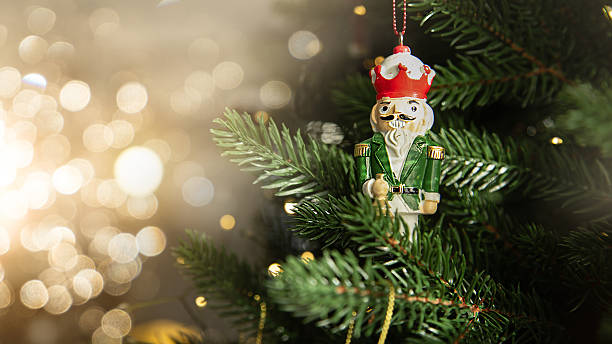 istock Traditional wooden nutcracker Christmas ornament hanging on a decorated Christmas tree with warm lights and golden baubles. Festive holiday atmosphere with cozy winter mood. 2251953096