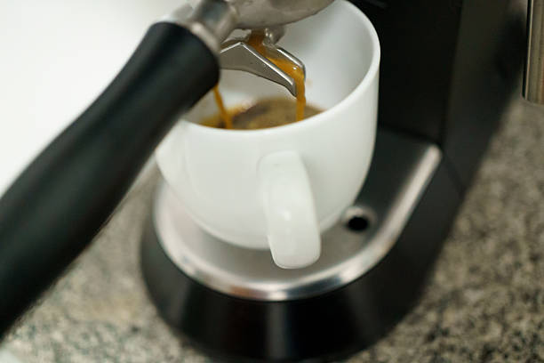 istock Espresso coffee pouring from machine spout into white cup 2251954980