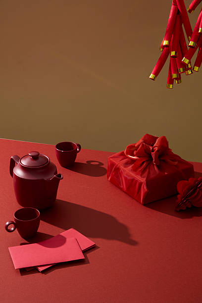 istock Red wrapped gift box with tea cups on red surface. Background representing Lunar New Year celebration, gifting season, and traditional Asian holiday themes. Vertical frame 2251955664