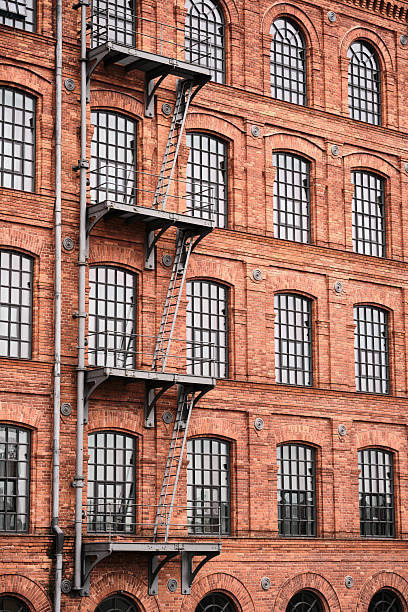 istock Red brick factory facade with metal fire escape 2251955997