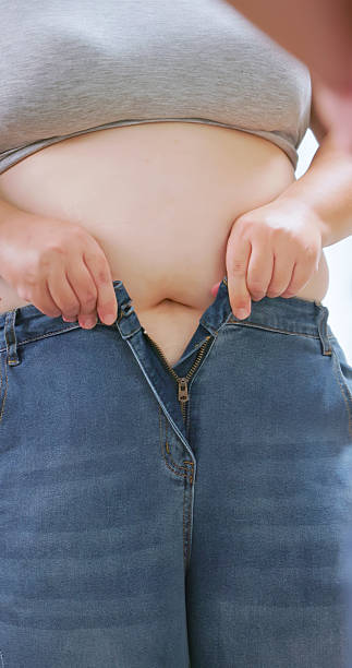 istock obese woman struggling to button her pants 2251956757