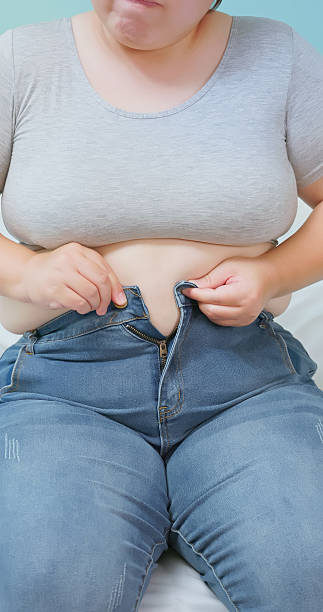 istock obese woman struggling to button her pants 2251956838