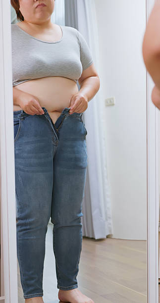 istock obese woman struggling to button her pants 2251956938