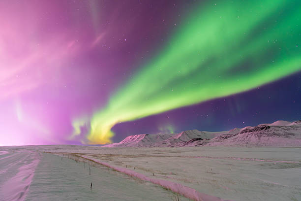 views of the aurora borealis dancing above snow-covered mountains. From above, the glowing Arctic sky contrasts with frozen peaks, revealing the vast and silent beauty of the winter landscape.