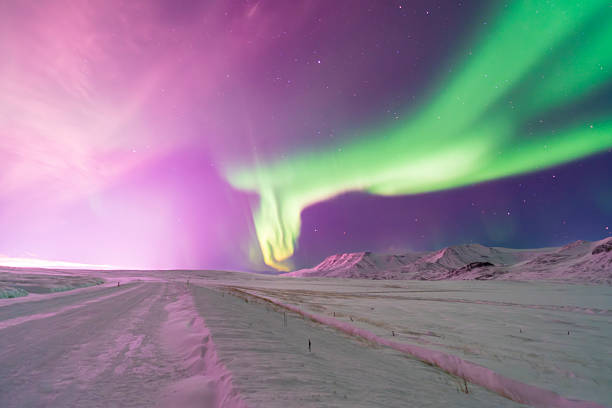 views of the aurora borealis dancing above snow-covered mountains. From above, the glowing Arctic sky contrasts with frozen peaks, revealing the vast and silent beauty of the winter landscape.