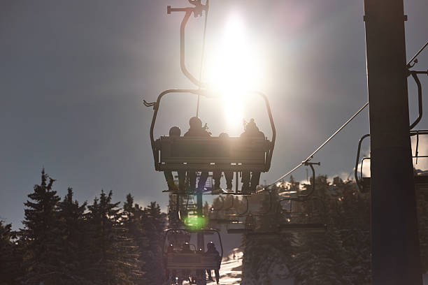 Back view of people riding on a ski lift during winter day on a mountain. Copy space.