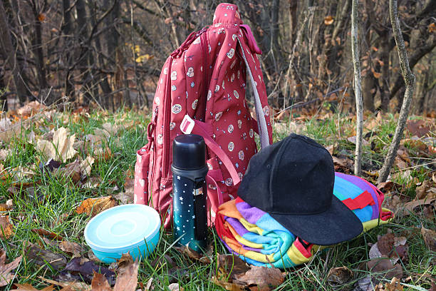 Tourist backpack, hiking boots, picnic utensils and hat on a path on the mountainside in the forest. Hike tourism outdoor recreation pi?nic camping concept