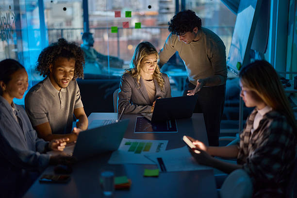 istock Team of creative colleagues working on laptops late in the office. 2251960444
