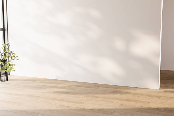 istock Minimalist empty room featuring a large white wall and light wood floor with natural shadows. Clean copy space for advertising and mock-ups. 3d Rendering 2251968479