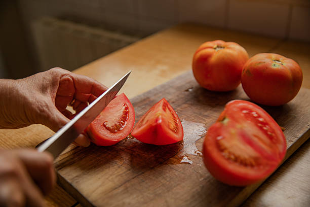 istock Cutting Fresh Tomatoes on Wooden Board 2251975355