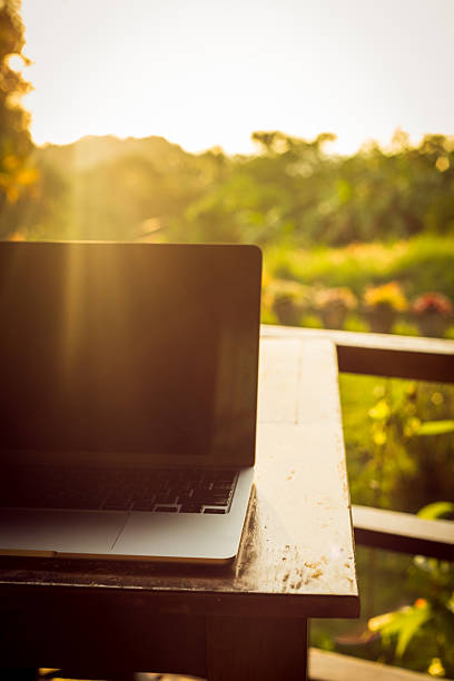 istock Laptop with backlight on wooden table on terrace in tropical forest at sunset, remote work digital nomad 2251977600