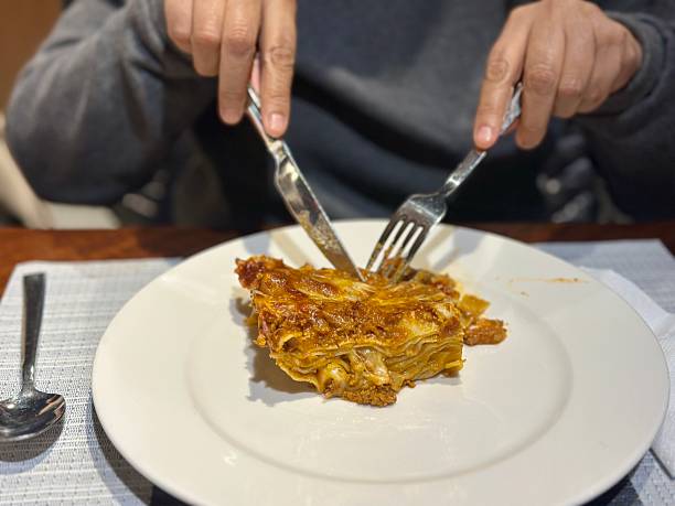 A plate of lasagna with cheese and meat on it. The plate is on a black background