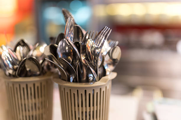 Shiny forks and spoons arranged in a plastic basket. Cutlery in a basket