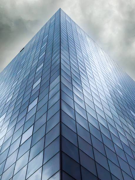 Modern glass skyscraper against a cloudy sky, showcasing architectural design and urban environment.