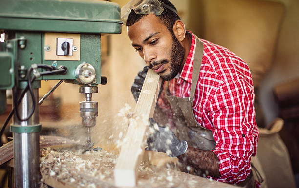 istock Multiracial Carpenter Skillfully Drilling Wood in Busy Workshop 2251988663